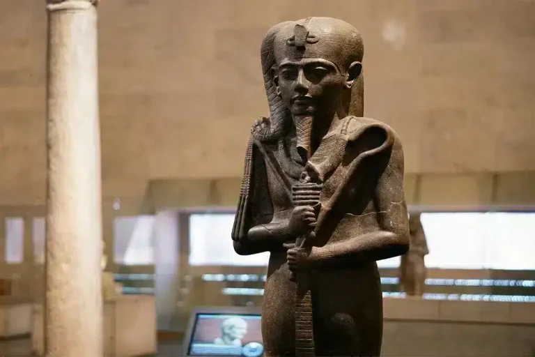 Statue of an ancient Egyptian figure in a museum setting.