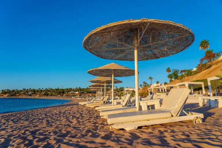 Beach loungers under straw umbrellas at Hurghada, pricing handmade crafts, handmade craft tags