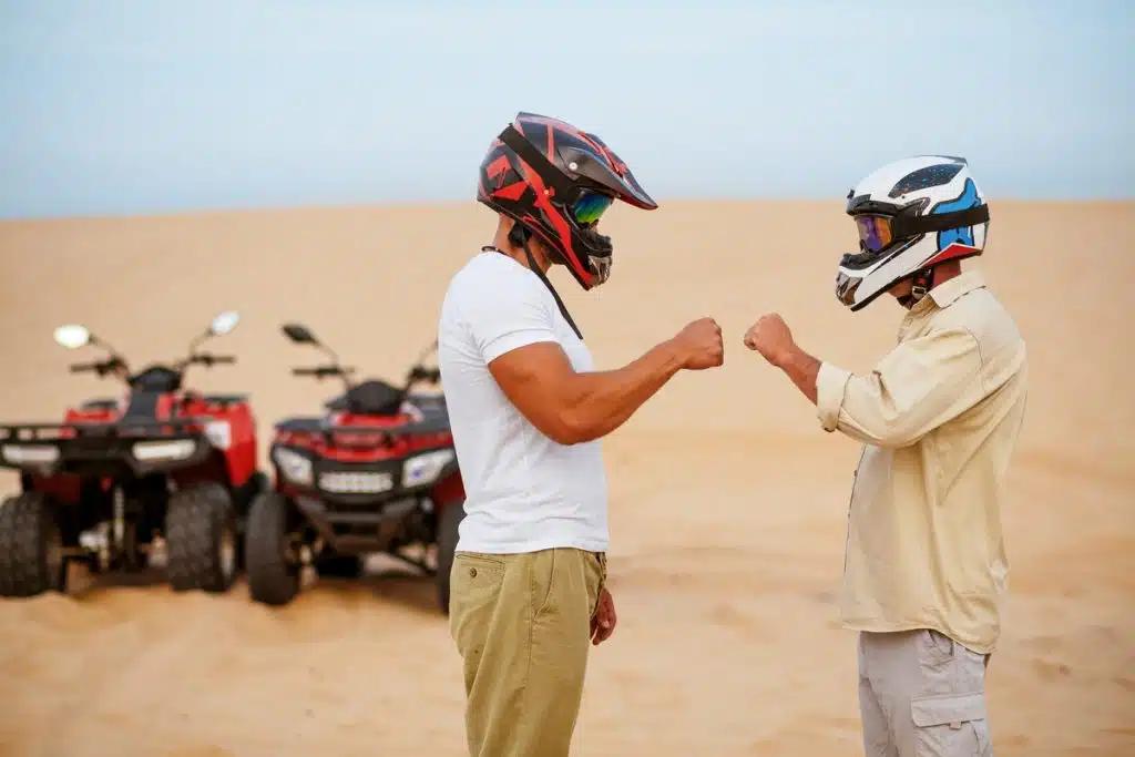 Two riders fist bump before their ATV adventure in the desert, part of an egyp egypt camel tour, pyramids of giza camel rides
